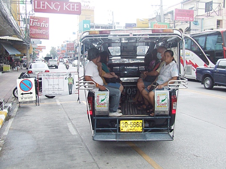A baht bus picks up passengers from a designated bus stop on Central Road.